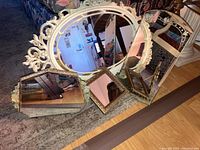 Set of four decorative mirrors placed on carpet next to sofa and a wooden chair, showing size and style variety.