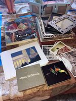 Overview of lot on tabletop showing fine art book, prints, postcards, and picture frames