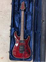 Full-length front view of red Schecter Hellraiser guitar in open hardshell case