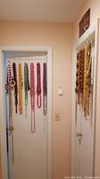 Photo of multiple beaded necklaces and bracelets hanging on hooks on a door and wall, showing various colors and bead styles