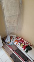 Corner with white woven fabric flags or banners, plastic wrapped, part of shoe shelf visible, rolled flags and poles on floor