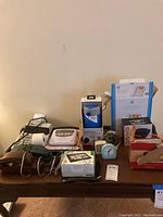 Full lot overview with items on table including GPS, receipt machine, cooler, clocks, and answering machine
