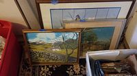 Three framed paintings leaning against a wall, showing all three pieces and their varying sizes.