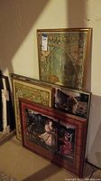 Four framed wall art pieces stacked leaning against wall