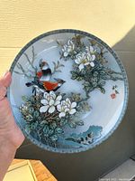 Front view of porcelain plate showing two birds on magnolia branches with floral design and border detailing