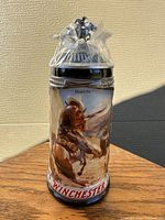 Front view of the ceramic stein showing colorful western artwork, pewter lid topped with horse and rider figurine, size about 9.5 inches tall.
