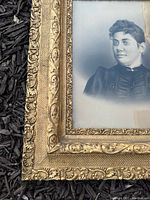 Close-up photo showing intricate gilded frame detailing with floral and scroll designs.