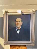 Full view of the framed portrait of a man showing the entire painting and carved wooden frame.