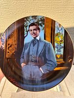Close-up photo of one Gone With The Wind collector plate featuring a male character in period clothing, detailed background, gold rim