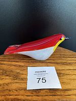 Side view of Murano style glass bird on wooden surface against black background showing color gradient details