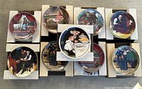 Top view of 10 Norman Rockwell collector plates, arranged in two rows, with different artwork scenes visible. Plates are on their original cardboard holders, appear new and unused.