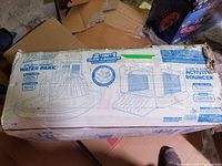 Outer cardboard box showing Banzai 2-in-1 Slide & Bounce Combo Park packaging with line drawings of water park and activity bouncer