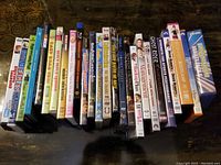 Photo showing 18 DVDs/BluRay movies arranged side-by-side with titles visible on spines and covers.