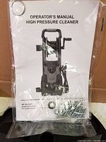 Operator's manual with image of the pressure cleaner on cover and mounting screws in clear bag.