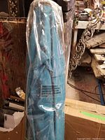 Blue UHINOOS 9FT patio umbrella folded and bagged in clear plastic, standing vertically.