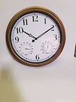 Full view of the round wall clock showing time, humidity, and temperature dials with a gold-toned frame.