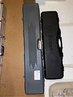 Two closed gun cases side by side, one gray Guard and one black Franchi.