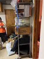 Full view of 6-shelf metal wire shelving unit holding various storage boxes and bags. Shows wire shelving design, metal posts, and contents not included.