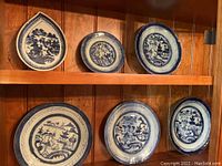 Three dishes on top shelf: pear-shaped, two round landscape plates