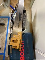 Disston Horseshoe hand saw with wooden handle laid atop Bosch carrying case, viewed from above.
