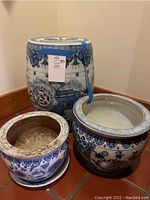 Overview of three blue and white ceramic items: drum-shaped garden stool and two round planters.