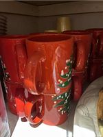 Photo of stacked large red Christmas mugs with green Christmas tree design