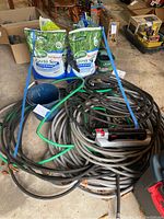 Overview of two bags of Scotts grass seed, garden hoses coiled, and a metal bucket.