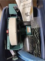 Top view of the green Grizzly slow speed grinder showing the white grinding wheel and attached instruction manual.