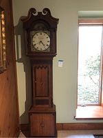 Front view of tall wooden clock showing overall structure and scale