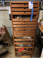 Tall narrow wood cabinet with ten shallow drawers in a workshop