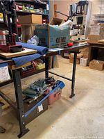 Shop Fox work bench with sturdy metal adjustable legs and cluttered workshop setting
