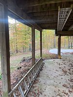 Werner aluminum extension ladder stored horizontally under deck on concrete floor with leaves around