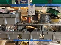 Shelving unit with multiple plastic bins holding spools of wire, hand tools, and hardware items.