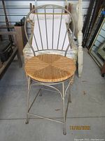 Front view of gray metal counter stool with woven rush seat showing design and condition.