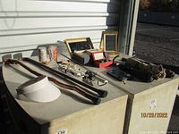 Wide view of the lot including two burl wood walking sticks, vintage collapsible umbrellas, a few boxed items such as the adjustable vanity mirror, hair appliances, and small containers.
