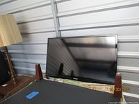 Samsung 32-inch TV resting on a table inside a storage unit, showing front view with screen and stand visible.