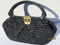 Full front view of the black woven taffeta handbag with braided handle and gold tone clasp showing its overall shape and material texture.