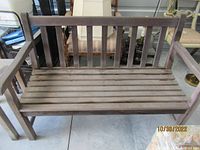 Full front view of weathered teak garden bench with slatted seat and back.