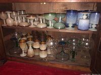 Wide view of two shelves showing multiple frosted gradient and clear stemmed glasses
