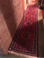 Entire red carpet runner laid out next to brick wall