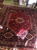 Angled full-view of carpet on green floor with wooden furniture and bookshelves in background.