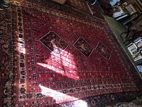 Full view of red hand woven carpet showing overall pattern, borders and condition.