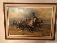 Frontal view of framed painting showing herd of galloping horses against landscape background