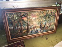 Full view of the large framed original painting on canvas with a landscape scene of trees, houses, and figures at tables near water.