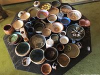 Overhead view of entire lot showing assorted bowls, plates, rings set on black table