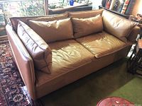 Front view of tan leather loveseat with cushions