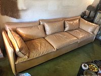 Front view of tan leather sofa showing three seat cushions and matching back cushions