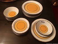 Full overview of stacked dinner plates, salad plates and bowls showing Sun pattern and speckled rims