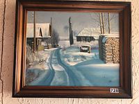 Front view of the framed painting showing a snow-covered rural scene with buildings, trees and wood stack