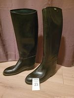 Front view of the black Aigle knee high rain boots standing upright showing overall shape and condition.